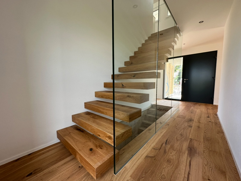 Moderne Holztreppe mit Glasgeländer in minimalistischem Wohnbereich. Elegantes Design für zeitgenössische Innenarchitektur.