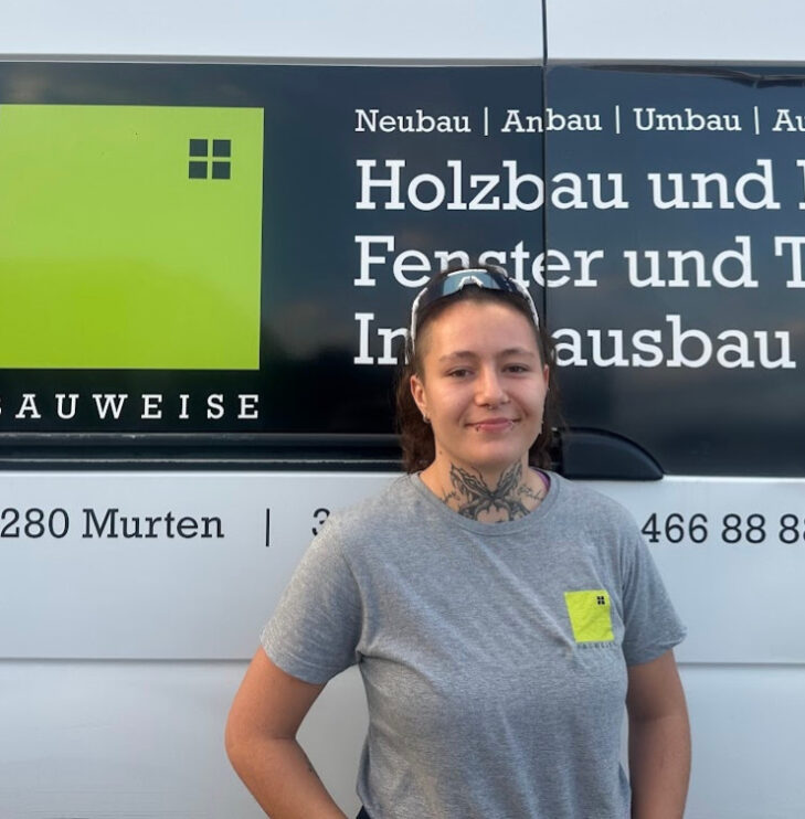 Person vor Bauweise-Fahrzeug, spezialisiert auf Holzbau und Innenausbau, lächelnd vor Logo und Kontaktinformationen.