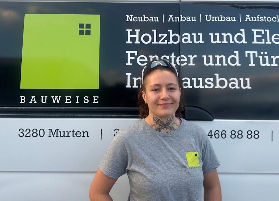 Person vor Bauweise-Fahrzeug, spezialisiert auf Holzbau und Innenausbau, lächelnd vor Logo und Kontaktinformationen.