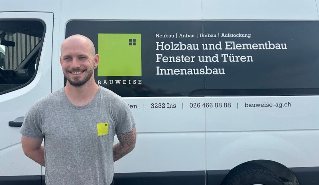 Lächelnder Mann vor Bauweise-Transporter mit Beschriftung für Holzbau und Innenausbau-Dienstleistungen.
